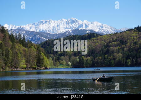Persona in una barca a remi su un lago insieme contro lo sfondo delle montagne maestose Foto Stock