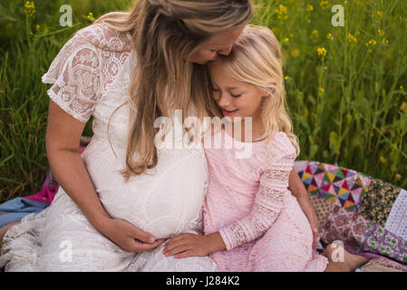 Elevato angolo di visione della madre baciare figlia sul fronte mentre è seduto in posizione di parcheggio Foto Stock