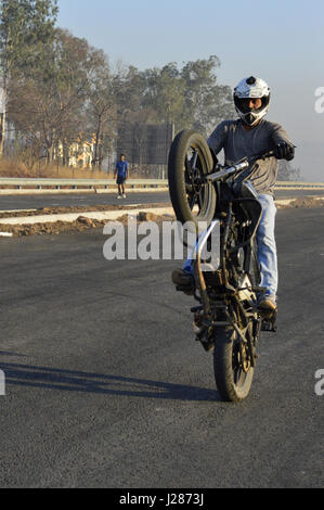 Stunt motociclista effettuando in corrispondenza di una strada locale vicino a Pune, Maharashtra Foto Stock