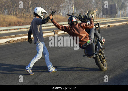 Stunt motociclista effettuando in corrispondenza di una strada locale vicino a Pune, Maharashtra Foto Stock