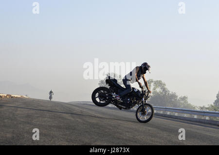 Stunt motociclista effettuando in corrispondenza di una strada locale vicino a Pune, Maharashtra Foto Stock