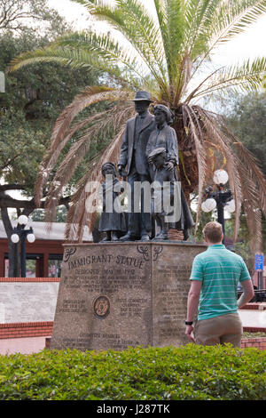 I turisti vista la statua di immigrati che si erge nel pubblico Centennial Park nella sezione vecchia di Ybor City, Florida. Foto Stock