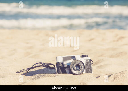 Vecchia fotocamera vintage giacente nella sabbia sulla spiaggia Foto Stock