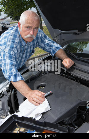 Uomo più anziano di pulizia motore auto con microfibra Foto Stock