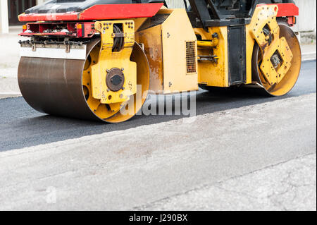 Pesante vibrazione compattatore a rulli in asfalto lavora per riparazione stradale Foto Stock