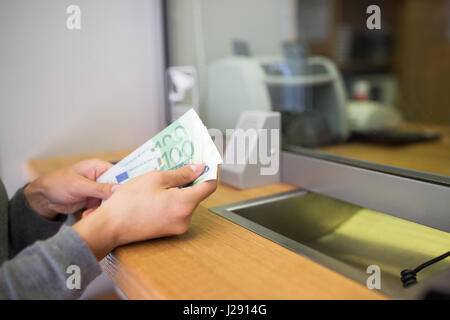 Le mani con i soldi in banca o scambiatore di valuta Foto Stock