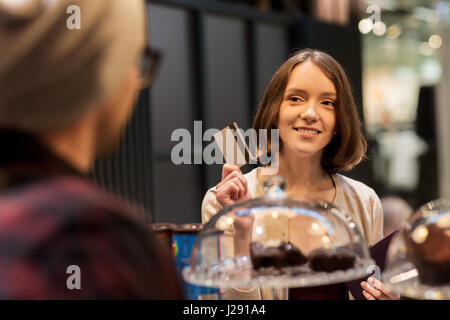 Donna felice con carta di credito acquisto di torte presso il cafe Foto Stock