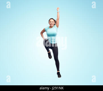 Sorridenti sportivo da donna giovane salti in aria Foto Stock