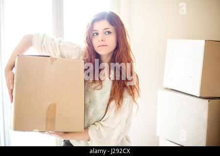 Grave Redhead donna Casa Azienda in movimento una scatola Foto Stock