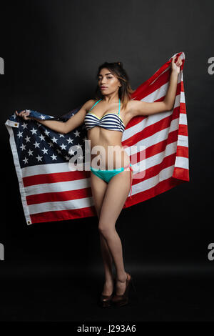 Allegro ispanica giovane donna americana holding bandiera nazionale in ambienti interni Foto Stock