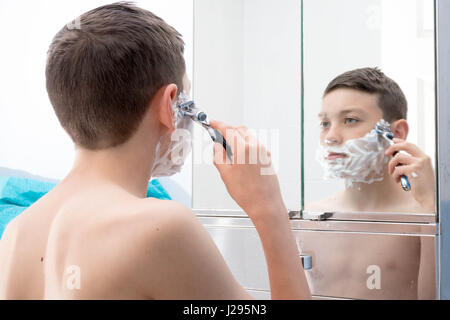 Giovane ragazzo adolescente la rasatura per la prima volta Foto Stock