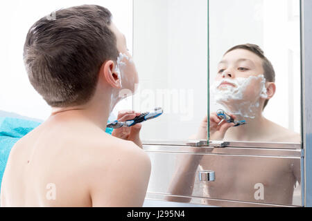 Giovane ragazzo adolescente la rasatura per la prima volta Foto Stock