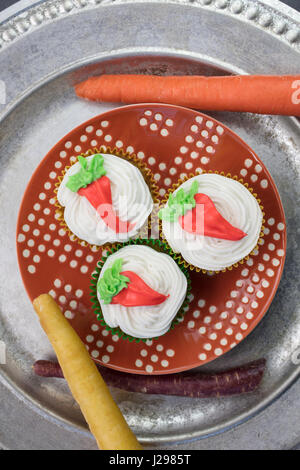 Dolce tortini di carote di fare con il bianco la glassa di formaggio cremoso e guarniti con arancio e giallo design di carota Foto Stock