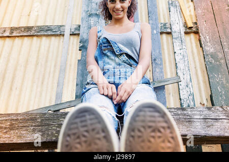 Giovane bella ragazza seduta nel parco con i suoi piedi in primo piano Foto Stock