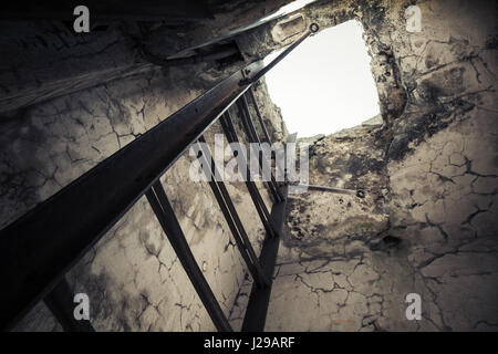 Vecchio vuoto bunker abbandonati interno con metallo arrugginito scaletta andando fino al tombino incandescente Foto Stock