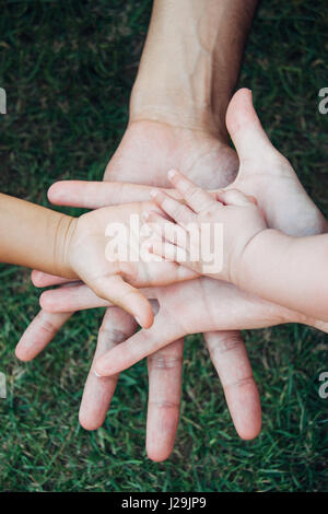 Quattro mani della famiglia, un bambino, una figlia di un padre e di una madre. Concetto di unità, supporto, protezione e felicità. Foto Stock