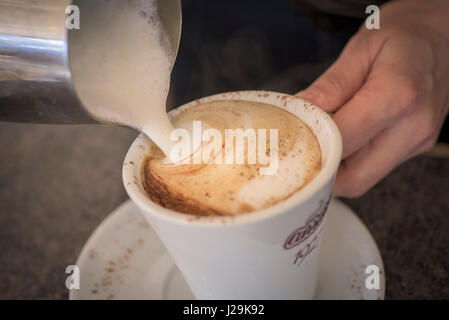Vista ravvicinata; Cappuccino; caffè; preparazione; preparazione; latte; latte; latte fresco; versato; versamento; barista; pausa caffè Foto Stock