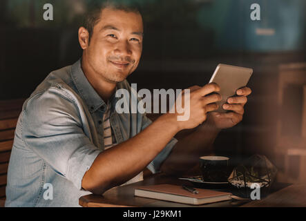 Contenuto uomo asiatico navigazione online mentre è seduto in un bar Foto Stock