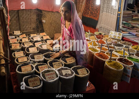 Una giovane donna vende spezie e tè presso il sabato notte di mercato in Arpora Foto Stock