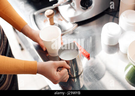 Barista fumante bidoni di latte per il cappuccino, macchina per il caffè, il fuoco selettivo Foto Stock