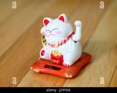 Un Maneki Neko-(letteralmente "fatto cenno cat' in Giapponese, conosciuta anche come la fortuna di un gatto, Cinese lucky cat o Happy cat) figurina. Un famoso fascino fortunato. Foto Stock