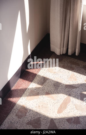 Di mattina presto lo streaming di luce attraverso una finestra e su un pavimento realizzato in terrazzo e la parete. Foto Stock