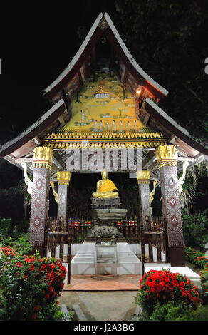 A GRANDEZZA NATURALE statua del Buddha in Bhumisparsha-toccando o chiamando la terra a testimoniare mudra-posizione di notte. Seduto Buddha Padiglione-Wat Xieng Thong- Foto Stock