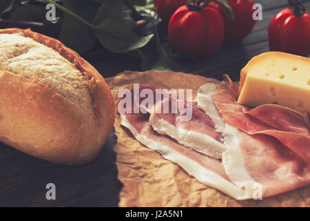 Brad, prosciutto e un vassoio di formaggi con alcuni pomodori su una tavola di legno Foto Stock