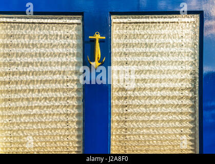 Vecchia porta di legno a casa con ottone respingente conformato come un elemento di ancoraggio, elemento del mare, arredamento vintage Foto Stock