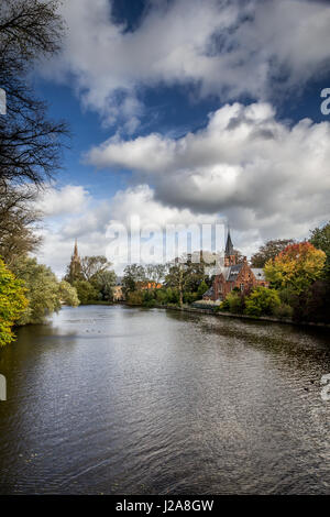 Lago romantico Minnewater in autunno con la sua famosa casa con torri e la chiesa di Nostra Signora a Bruges, Belgio. Vista verticale. Foto Stock