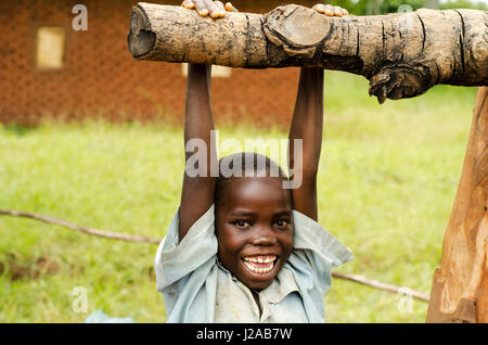 Il Malawi, Mzimba distretto, Chilumba basato sulla comunità Centro per l'infanzia (CBCC). Sorridente ragazzo africano appeso asta di legno Foto Stock