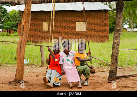 Il Malawi, Mzimba distretto, Chilumba basato sulla comunità Centro per l'infanzia (CBCC). Sorridenti dei bambini che giocano su legno swing Foto Stock