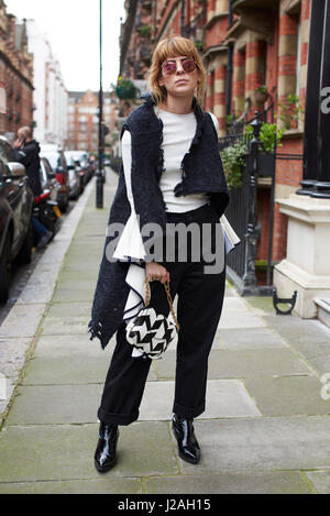 Londra - febbraio, 2017: piena lunghezza Ritratto di fashion blogger Xeni Kouveli in piedi in strada holding Ferragamo borsetta, London Fashion Week, giorno 4. Foto Stock
