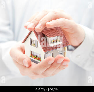 La protezione della casa. Piccola casa giocattolo in mani Foto Stock