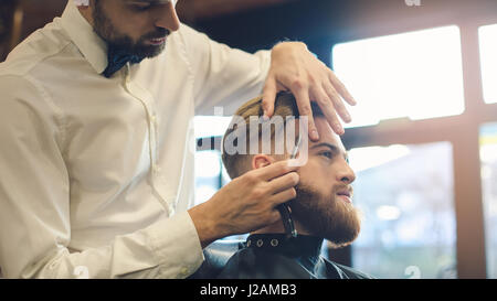 Giovane uomo in Barberia per la cura dei capelli il concetto di servizio Foto Stock