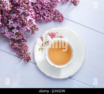 Tazza di tè e rami di fioritura lilla sul tavolo di legno. Foto Stock