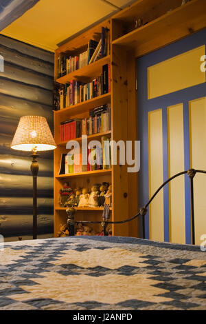 Vista parziale del letto e una pineta libreria nella camera ospiti all'interno di un country cottage in stile residenziale home registro Foto Stock