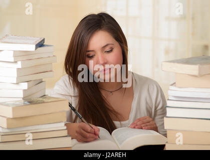 Stanco ragazza studente iscritto e addormentarsi con libri in biblioteca Foto Stock