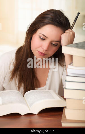 Stanco studente ragazza di addormentarsi la lettura di un libro in biblioteca Foto Stock