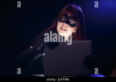 Bruna in maschera con il computer portatile Foto Stock
