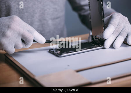 Dettaglio immagine del maschio di spazzolatura tecnico all'interno di smart phone al negozio di elettronica Foto Stock