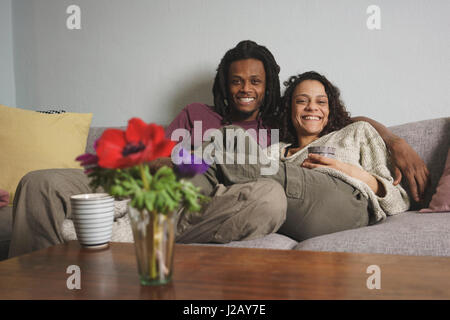 Ritratto di felice multi-etnico giovane rilassante sul divano di casa Foto Stock