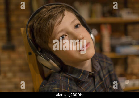 Riflessivo ragazzo ascoltando la musica attraverso le cuffie a casa Foto Stock