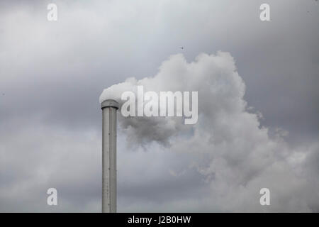 Basso angolo di visualizzazione ad emissione di fumo dal camino contro il cielo nuvoloso Foto Stock