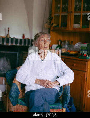 Riflessivo senior donna seduta sulla poltrona di casa Foto Stock