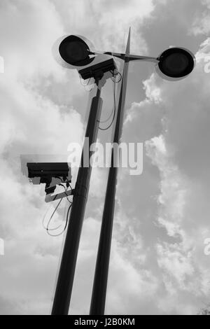 Multi-layered immagine delle telecamere di sicurezza e le luci di strada contro il cielo nuvoloso Foto Stock