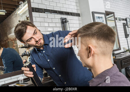 Giovani parrucchiere utilizzando mousse sul cliente i capelli al Barber shop Foto Stock