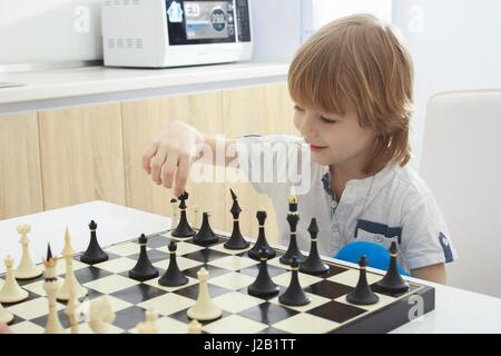 Piccolo ragazzo intelligente concentrato e pensare con gli scacchi Foto Stock