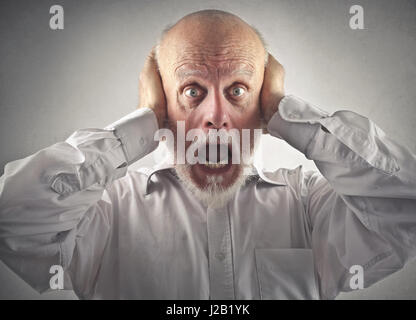 Paura di vecchio uomo che copre le sue orecchie Foto Stock