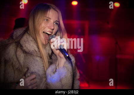 Giovane donna cantare karaoke Foto Stock